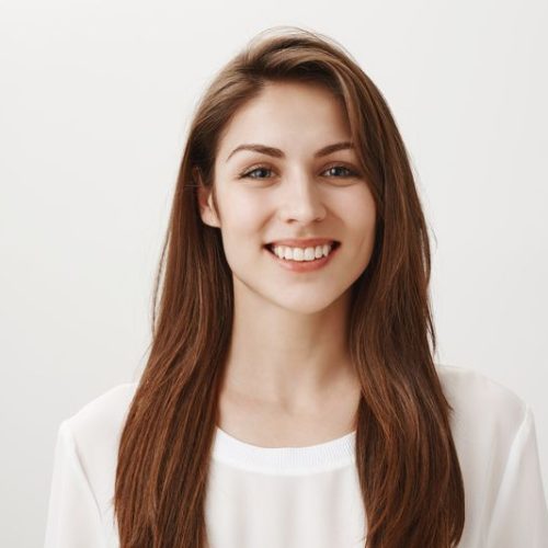 Girl is happy receive good feedback about her site. Portrait of attractive caucasian woman in white shirt smiling broadly, looking with satisfied expression at camera, feeling great after day in spa. Emotions concept